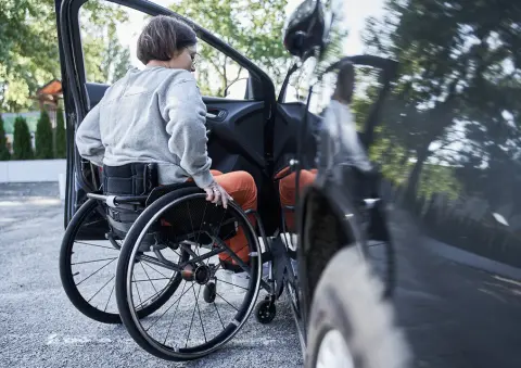 Wheelchair user getting into a car in a hospital car park